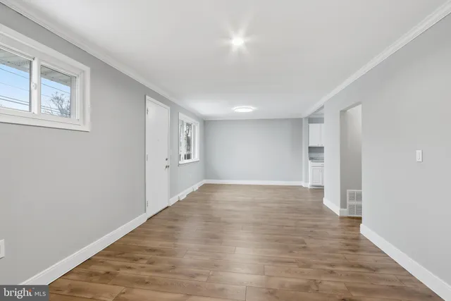 a view of an empty room with wooden floor and windows