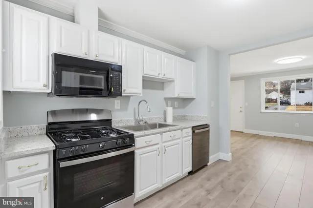 a kitchen with granite countertop a stove a sink and a microwave