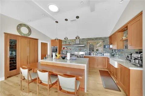 a large white kitchen with a large window and stainless steel appliances