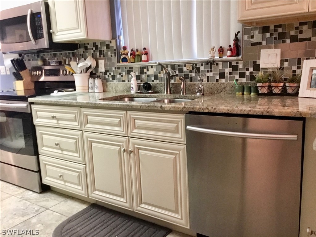 15550 Burnt Store Road, Unit 13 Punta Gorda, FL 33955 - Photo 19 of 30 a kitchen with stainless steel appliances granite countertop a sink and a white cabinets