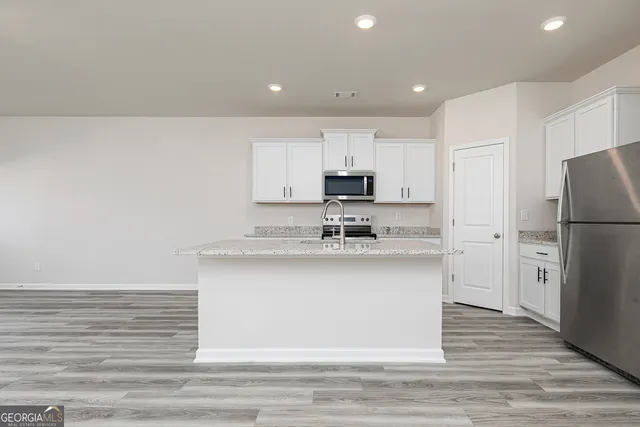 a kitchen with granite countertop white cabinets and stainless steel appliances