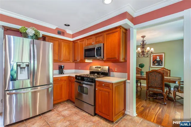 a kitchen with stainless steel appliances granite countertop a stove top oven a refrigerator and a dining table with wooden floor