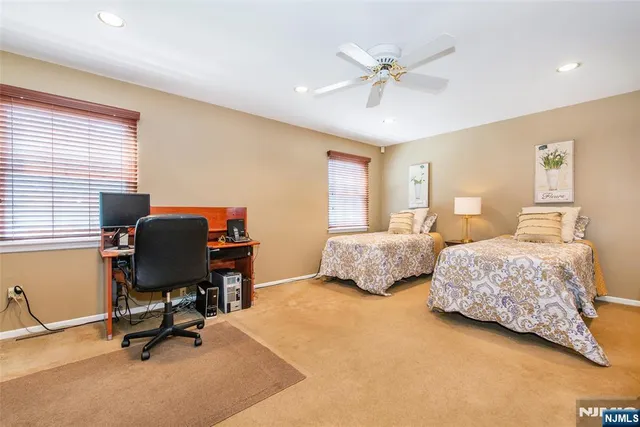a bedroom with two beds and a ceiling fan