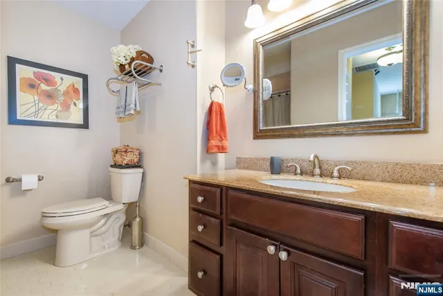 a bathroom with a granite countertop sink a toilet and a mirror