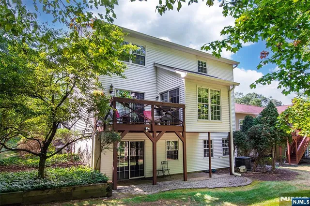 a view of a white house with a small yard and large tree