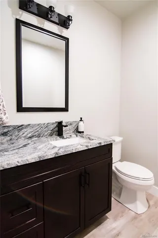 a bathroom with a granite countertop sink a toilet and mirror