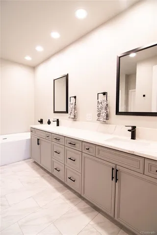 a spacious bathroom with double vanity a mirror a bathtub and double
