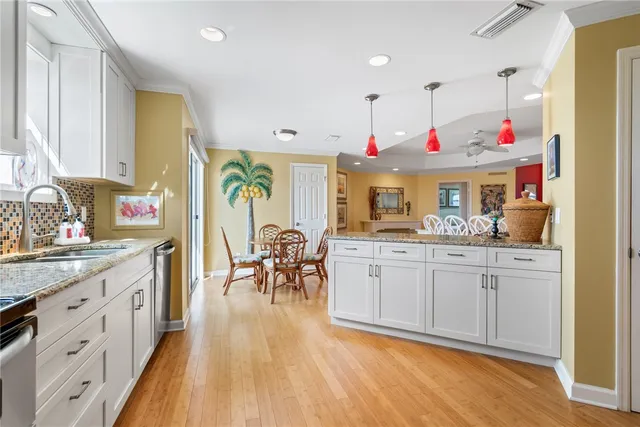 a very nice looking open kitchen with granite countertop a stove a sink a dining table and chairs with wooden floor