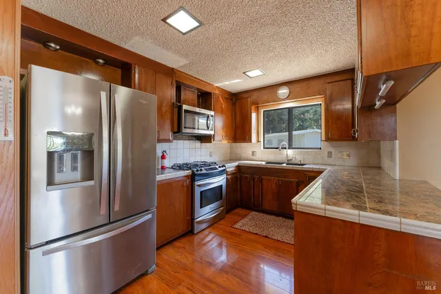 a kitchen with stainless steel appliances granite countertop a refrigerator a stove top oven a sink and dishwasher