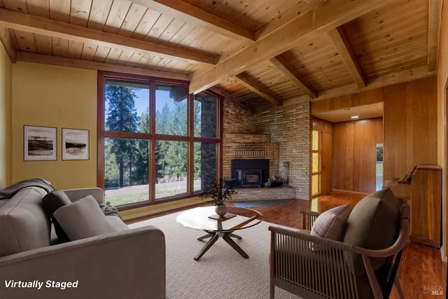 a living room with furniture a fireplace and a floor to ceiling window