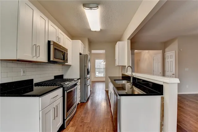 a kitchen with granite countertop cabinets stainless steel appliances and wooden floor