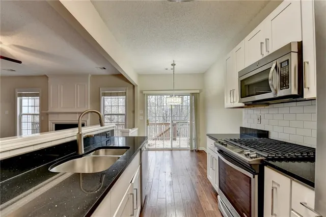 a kitchen with granite countertop a sink and white cabinets with wooden floor