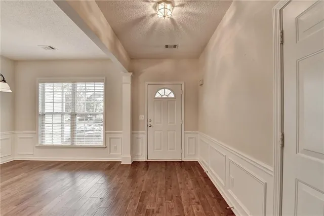 a view of an empty room with chandelier and wooden floor