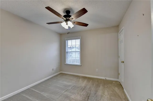 an empty room with a window and ceiling fan