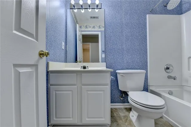 an empty room with chandelier fan and windows