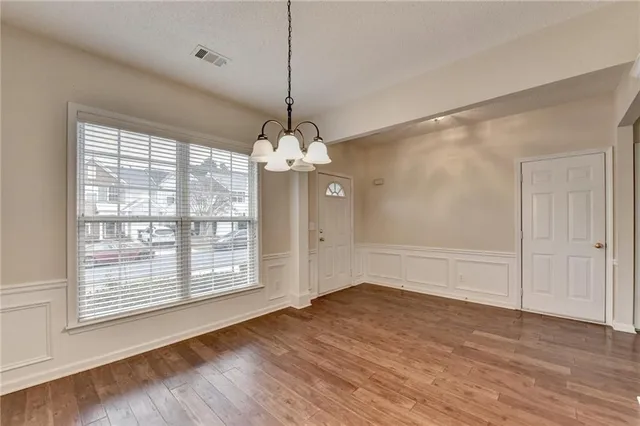 a view of an empty room with wooden floor fireplace and a window
