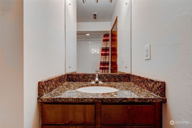 a bathroom with a granite countertop sink and a mirror