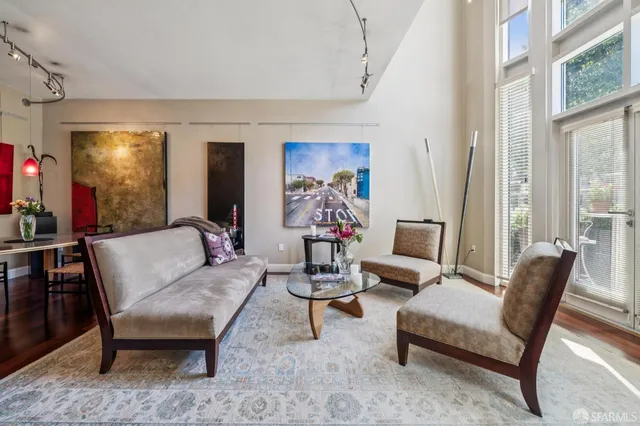 a living room with furniture and a large mirror next to a window