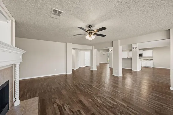 a view of an empty room with wooden floor and a fireplace