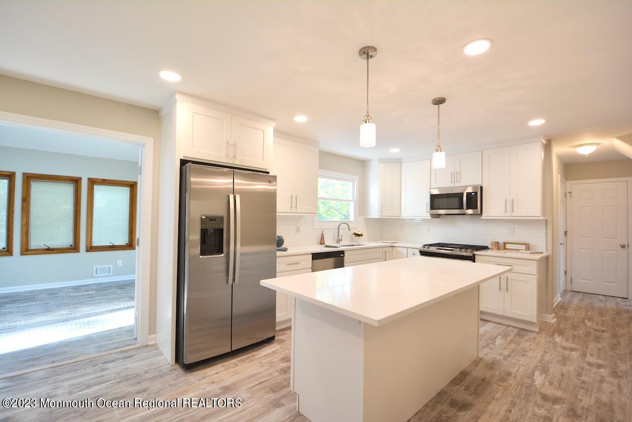 6 Wickatunk Road Manalapan, NJ 07726 - Photo 4 of 35 a kitchen with stainless steel appliances kitchen island granite countertop a refrigerator a sink a stove and a wooden floors