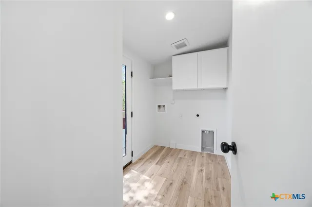 a view of a kitchen with white cabinets and wooden floor