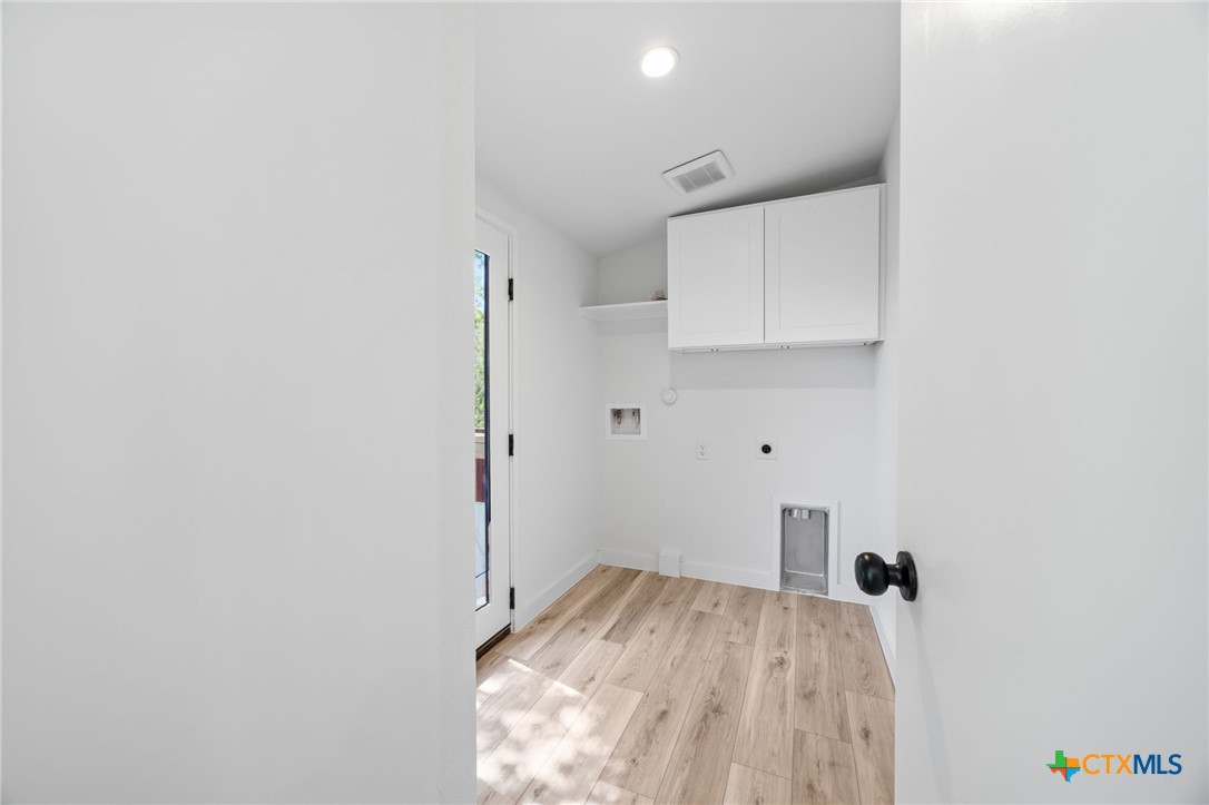 404 East Pecan Street Taylor, TX 76574 - Photo 17 of 19 a view of a kitchen with white cabinets and wooden floor