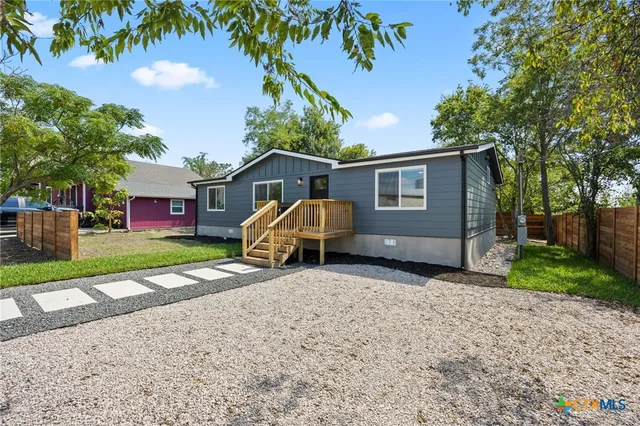 a view of a house with a yard and large tree