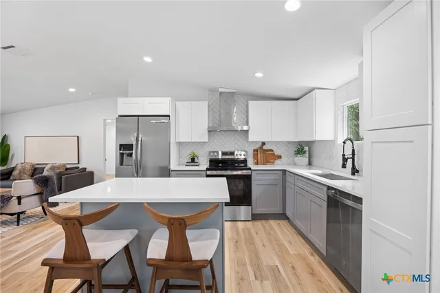 a kitchen with stainless steel appliances kitchen island granite countertop a dining table chairs and sink