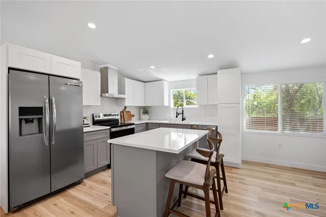 a kitchen with kitchen island a counter top space cabinets and stainless steel appliances