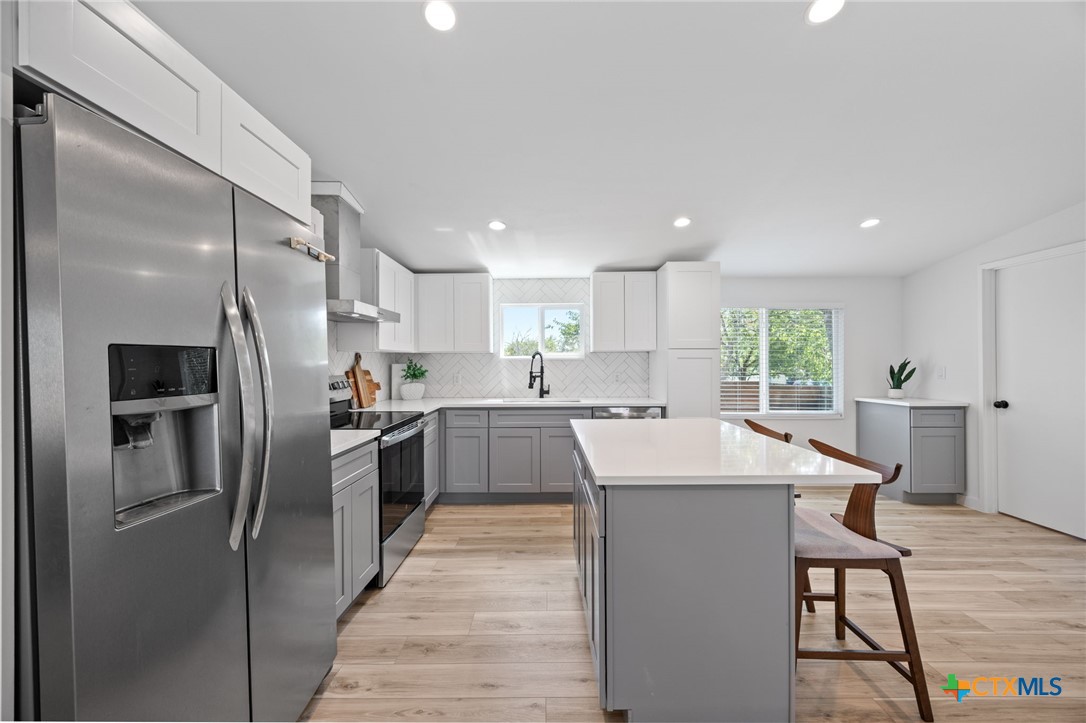 404 East Pecan Street Taylor, TX 76574 - Photo 8 of 19 a kitchen with stainless steel appliances kitchen island granite countertop a refrigerator a sink a stove a dining table and chairs