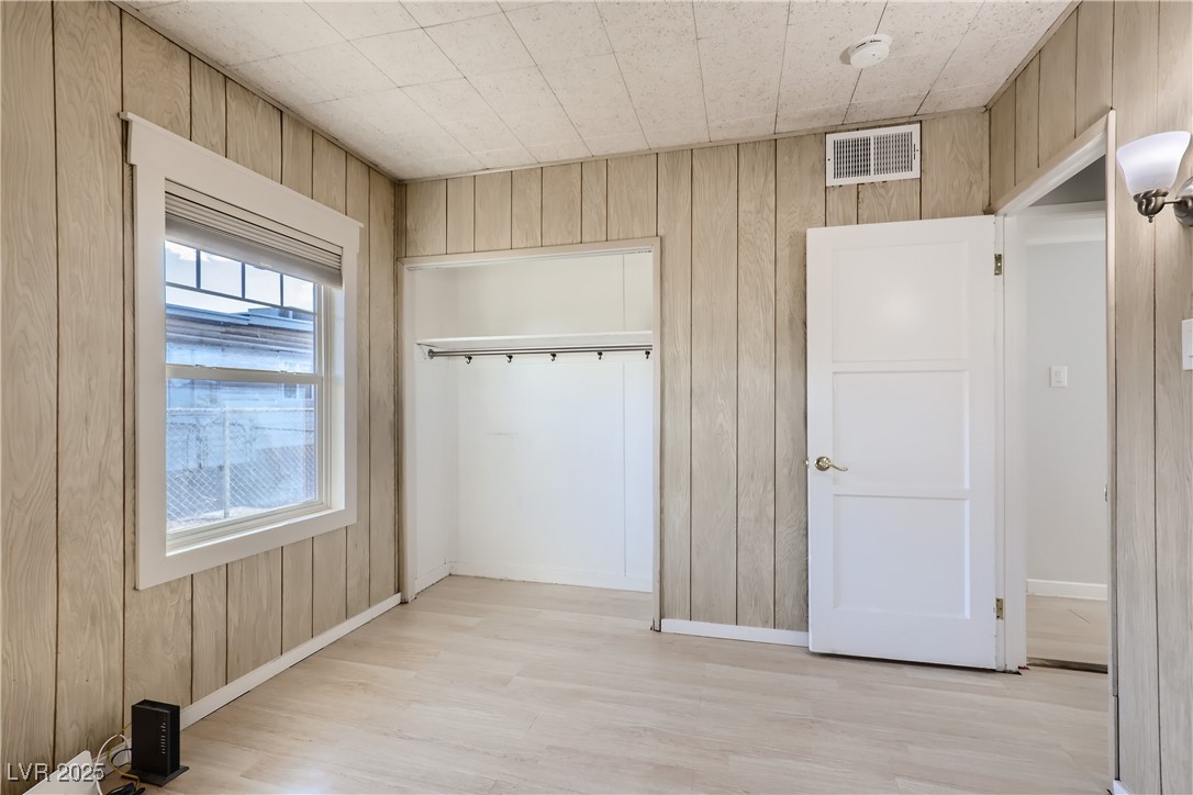 103 West Victory Road Henderson, NV 89015 - Photo 21 of 28 Unfurnished bedroom with light wood-type flooring, wood walls, baseboards, and a closet