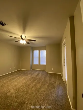 an empty room with windows and fan