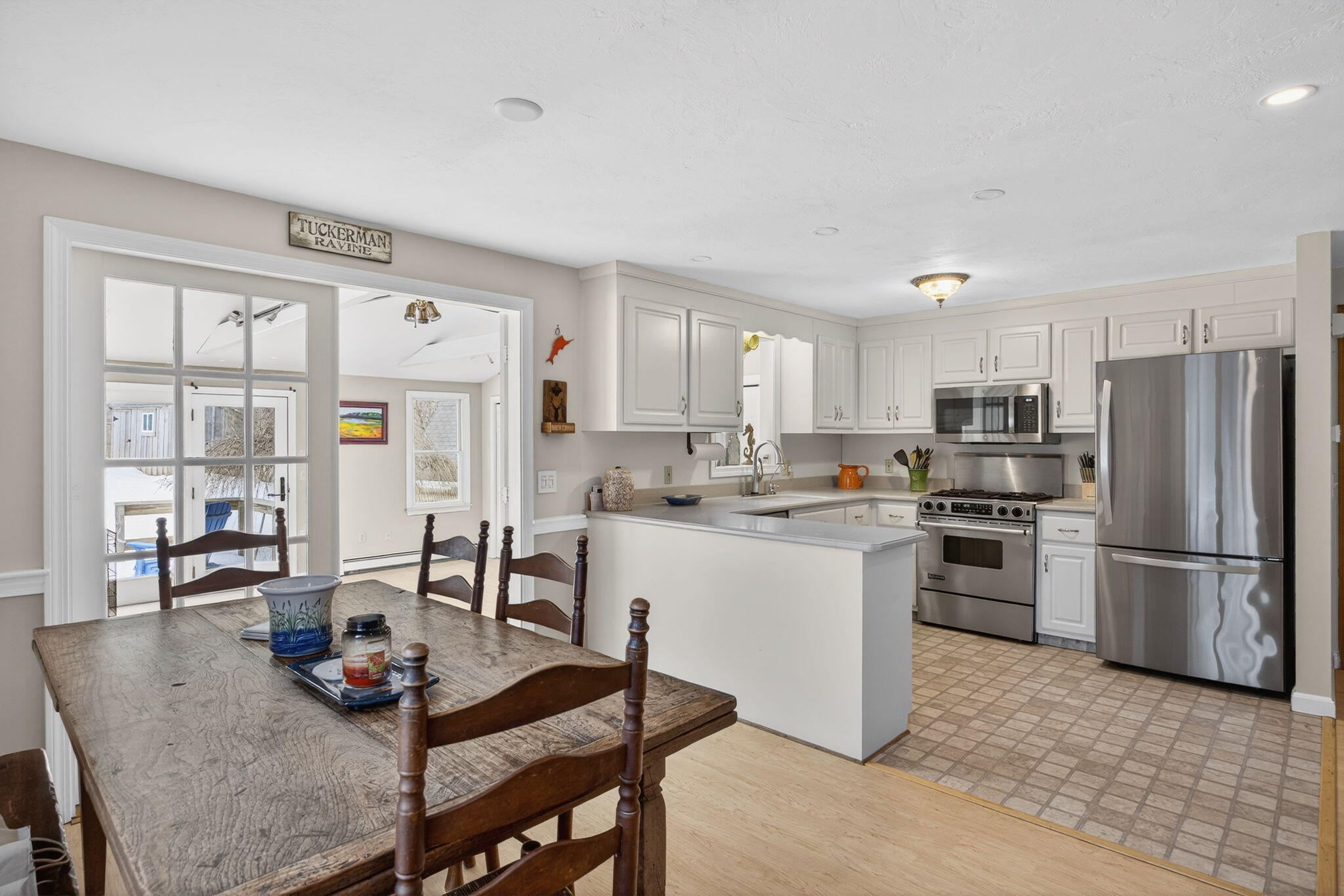 171 Weir Road Yarmouth Port, MA 02675 - Photo 22 of 53 a kitchen with stainless steel appliances granite countertop a stove a refrigerator a sink a dining table and chairs with wooden floor