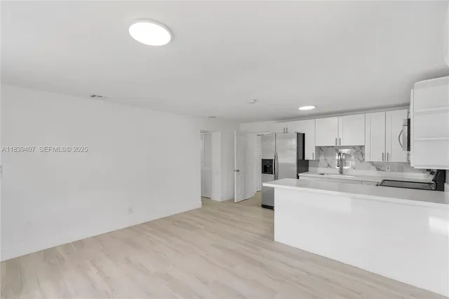 a large white kitchen with wooden floor and a sink