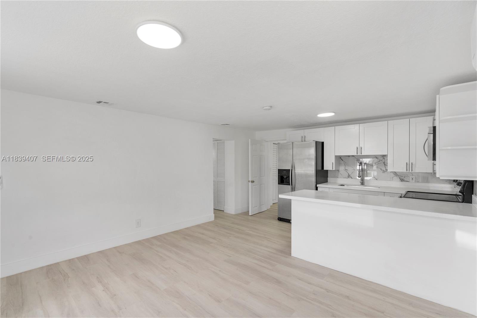 607 Southwest 3rd Street, Unit 1 Delray Beach, FL 33444 - Photo 12 of 27 a large white kitchen with wooden floor and a sink