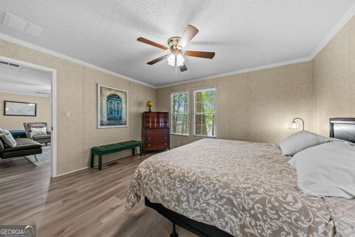 194 Phillips Road Eatonton, GA 31024 - Photo 21 of 57 a bedroom with a large bed a chandelier and windows