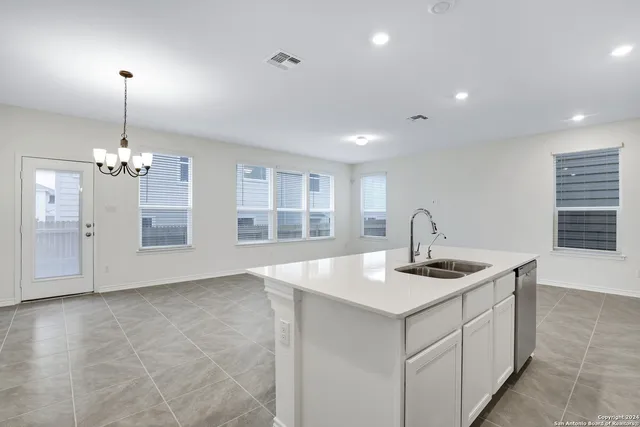 a kitchen with kitchen island granite countertop a sink and white cabinets