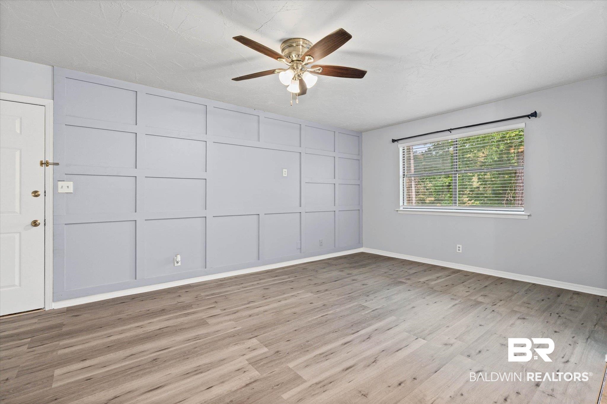 500 Grant Street, Unit C210 Daphne, AL 36526 - Photo 4 of 26 Spacious room featuring a decorative accent wall, wood-finish flooring, and a ceiling fan with integrated lighting
