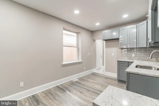 a kitchen with granite countertop white cabinets appliances and a window