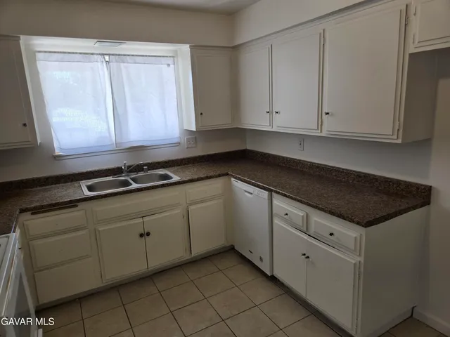 a kitchen with granite countertop white cabinets and sink