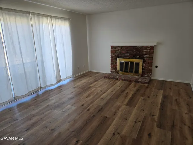 a view of a livingroom with wooden floor and a fireplace