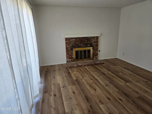 a view of empty room with wooden floor and fireplace