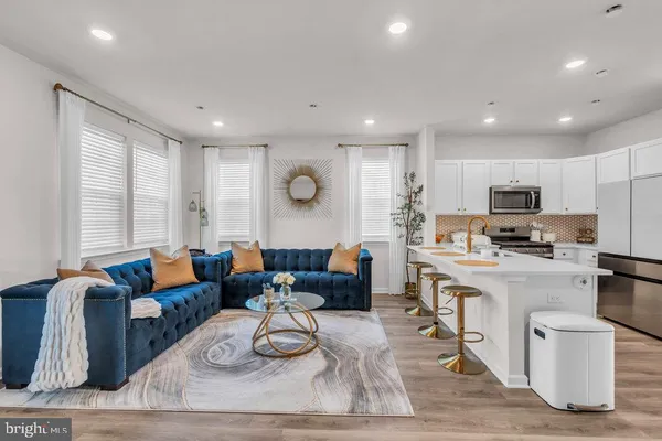 a living room with furniture wooden floor and kitchen view