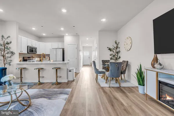 a living room with stainless steel appliances furniture wooden floor and a view of kitchen