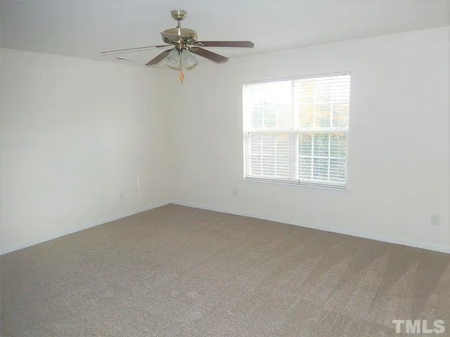an empty room with a window and a fan