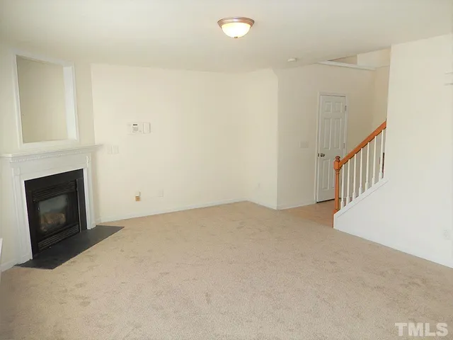 a view of an empty room with wooden floor and a fireplace