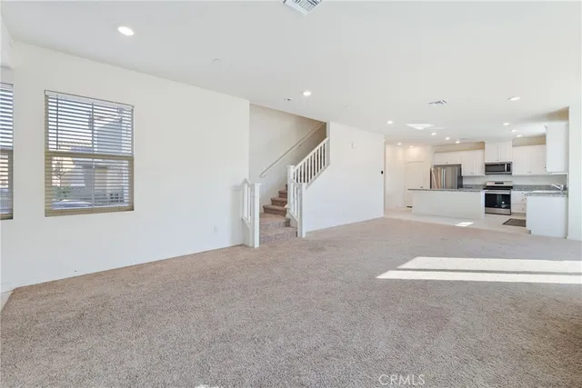 a view of a big room with windows and chandelier fan