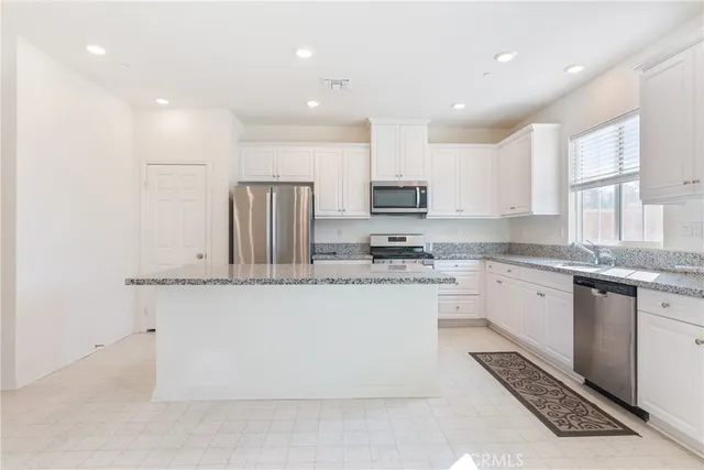 a kitchen with stainless steel appliances granite countertop a refrigerator sink and white cabinets
