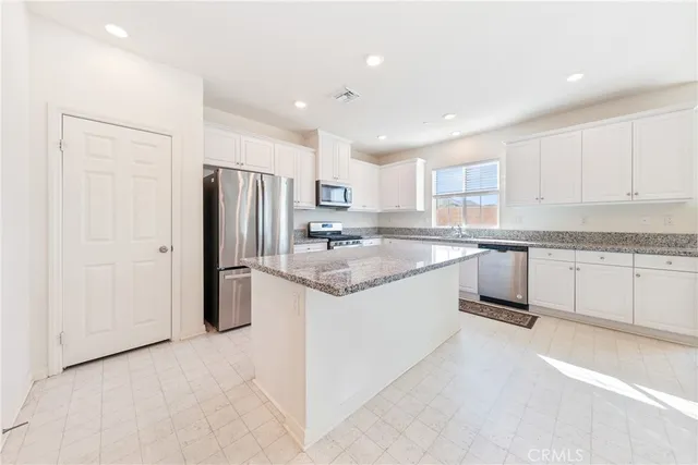 a kitchen with granite countertop kitchen island a sink appliances and cabinets