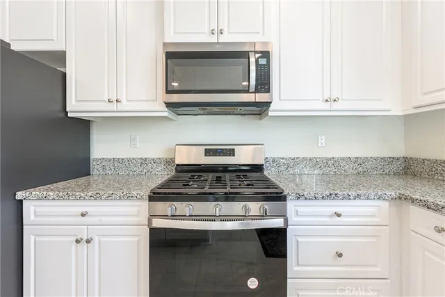 a kitchen with granite countertop white cabinets and a window